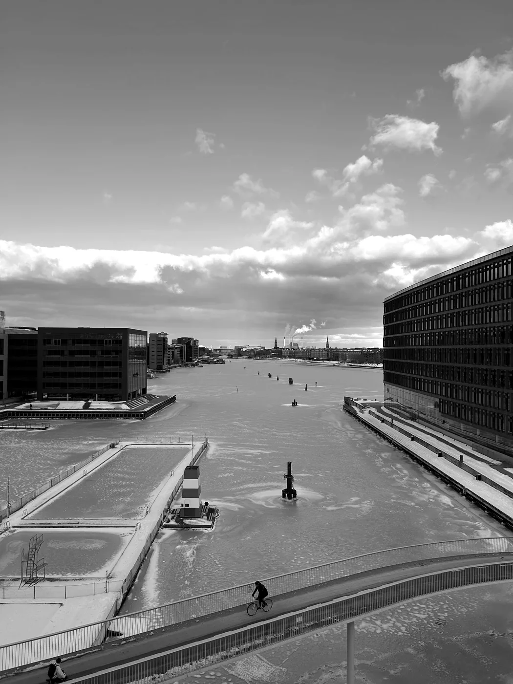 A cyclist crossing a bridge over the frozen Copenhagen canal in winter