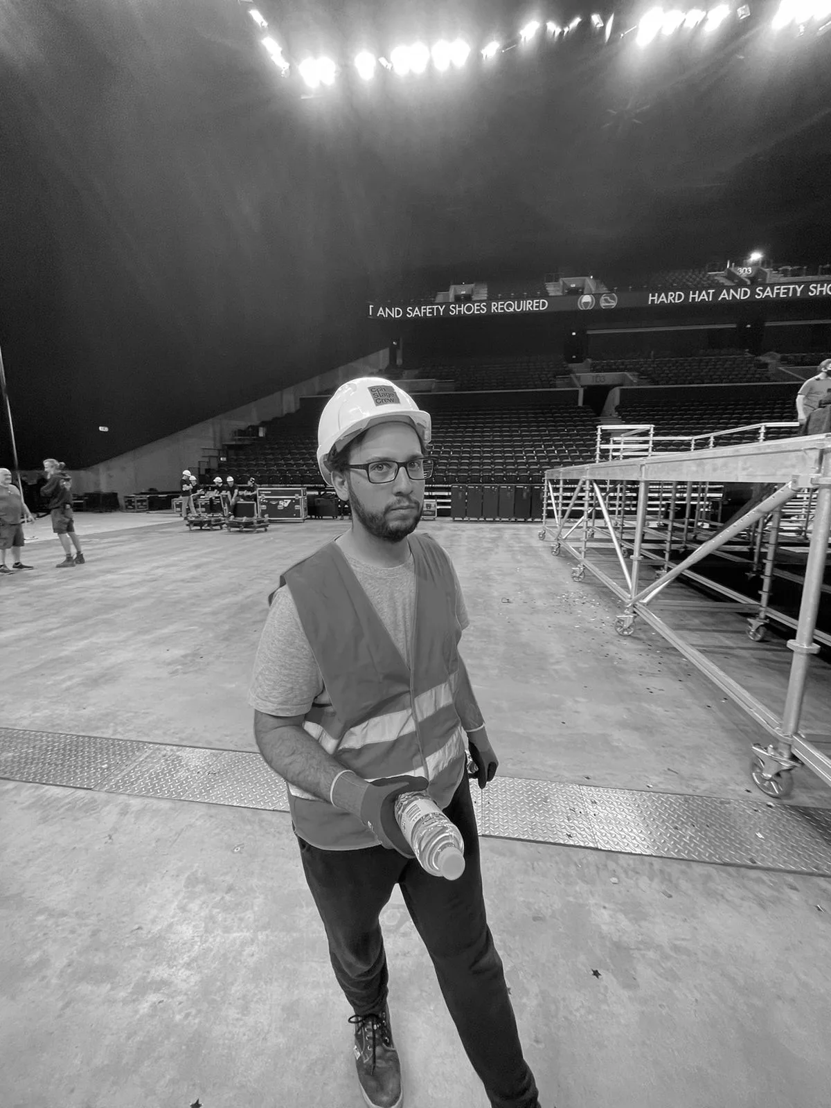 Franco in a hard hat and safety vest on an arena floor during a live event build