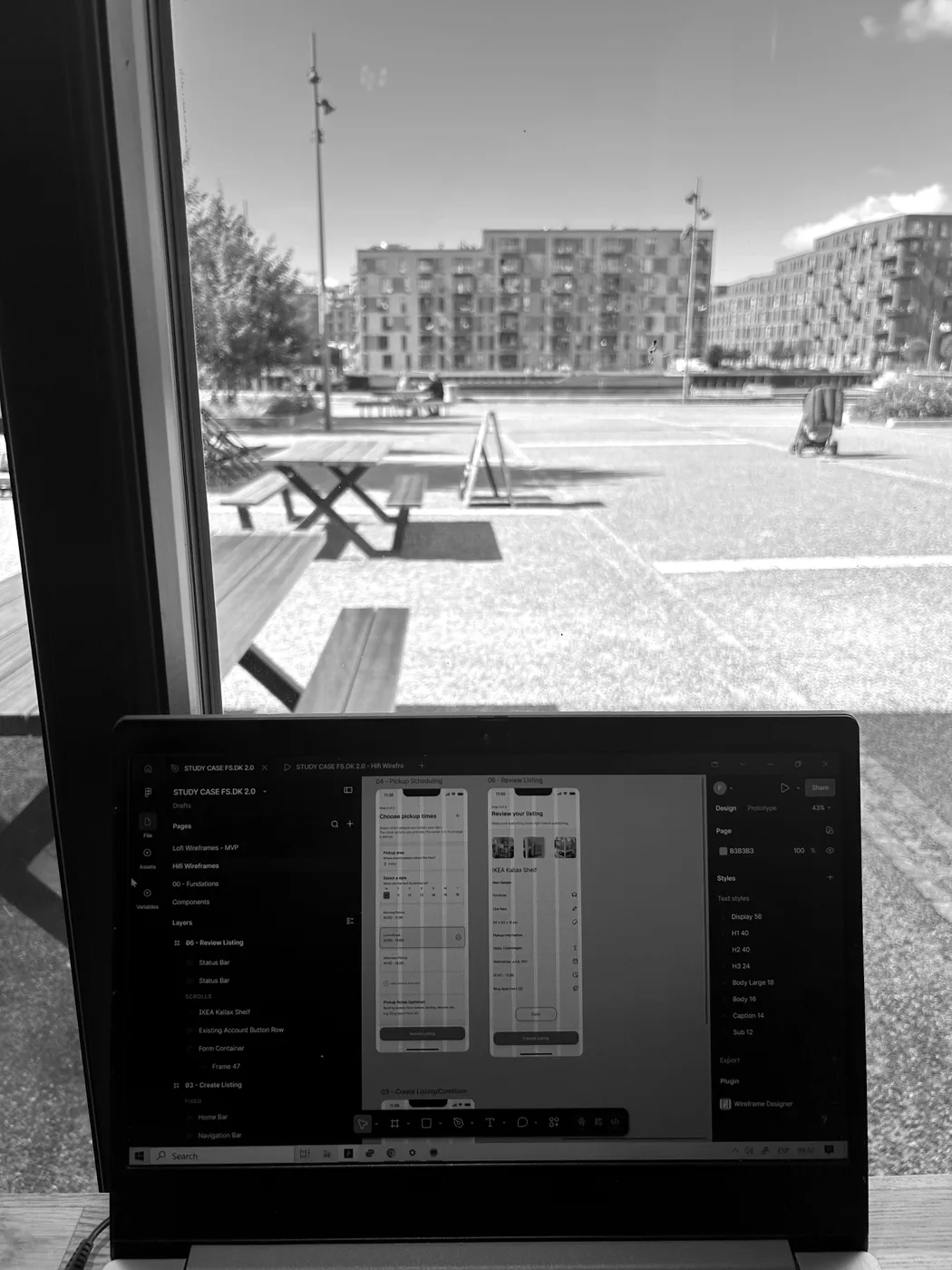 Franco's laptop showing high-fidelity FS.dk wireframes, seen from behind on a café table by the Copenhagen harbour